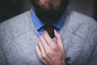 A man wearing men’s casual officewear adjusting his tie