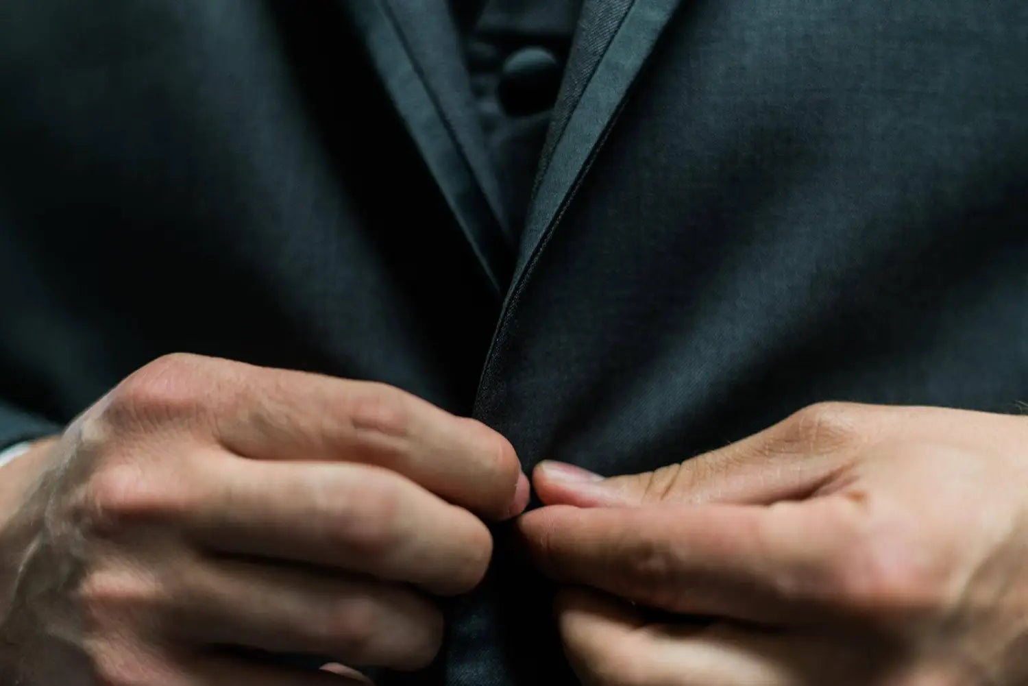 A man buttoning his black suit
